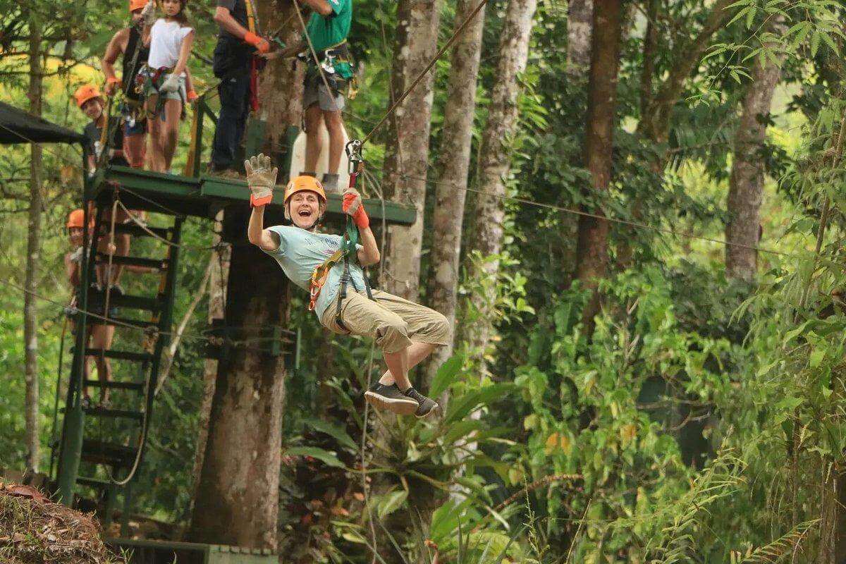 Adventurer soaring through the trees on a zipline during the Manuel Antonio canopy tour